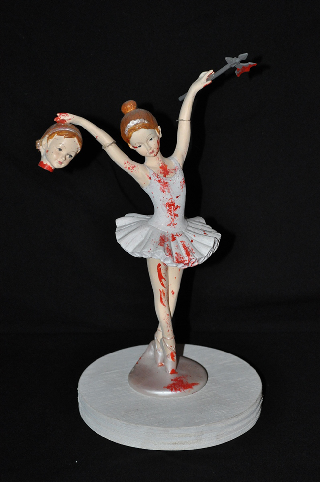 Statue of a ballerina with a head in one hand and an axe in the other hand