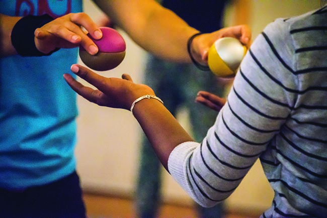 Woman handing juggling balls over to another woman.